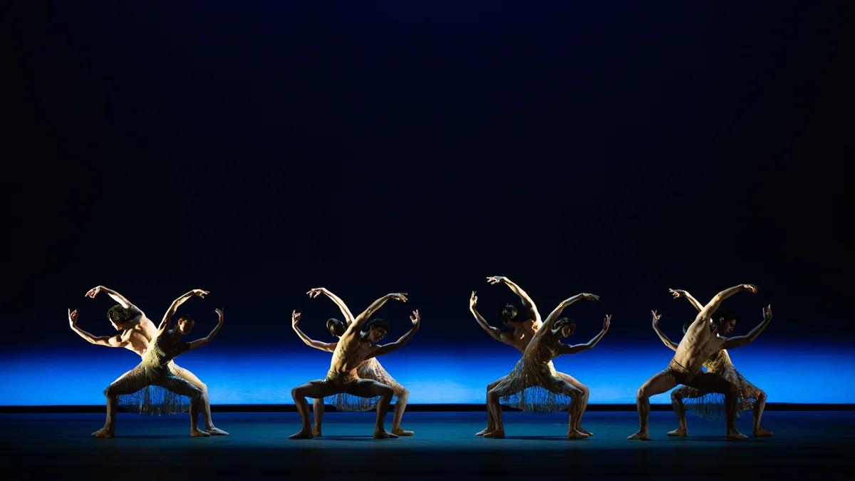 Four pairs of dancers form sweeping shapes against a blue-lit stage in Within the Golden Hour.